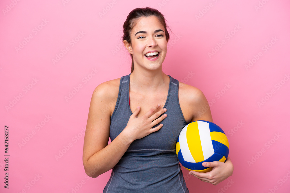 Young Brazilian woman playing volleyball isolated on pink background smiling a lot