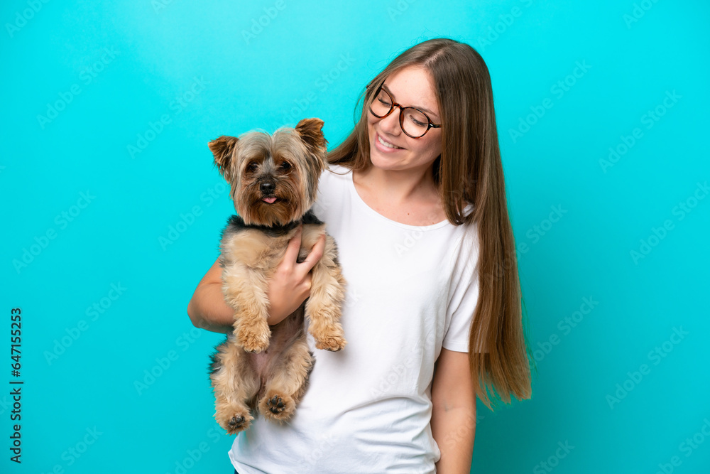 Young Lithuanian woman holding a dog isolated on blue background with happy expression Young Lithuanian woman holding a dog isolated on blue background with happy expression