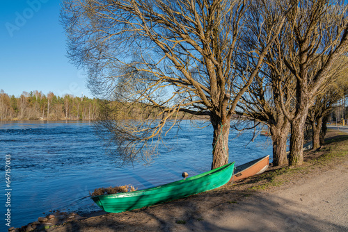 View of Vuoksi river and river banks in spring, trees, boat and water, Mellonlahti, Imatra, Finland photo