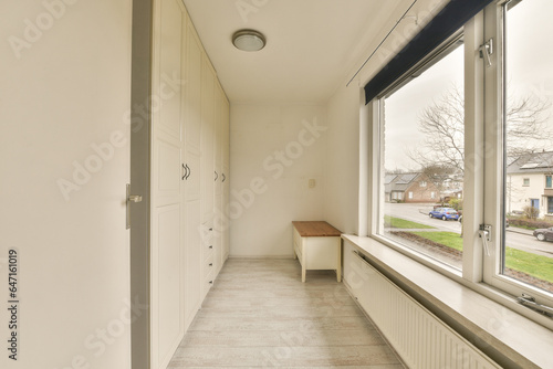 the inside of a room with a window and white cupboards on either side, looking out onto the street