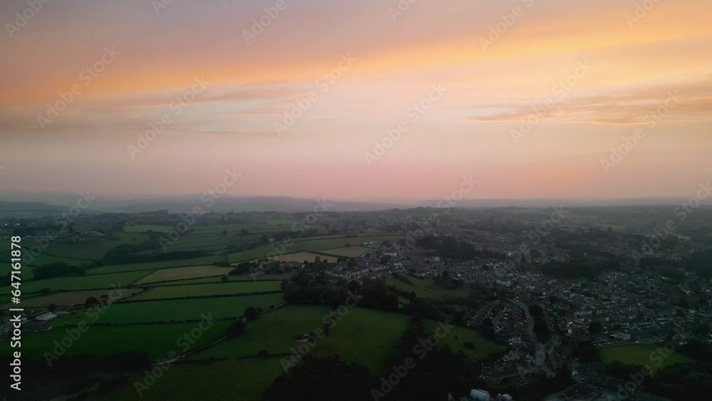 Experience Heckmondwike, UK, through captivating drone-shot aerial footage, highlighting industrial structures, lively streets, and the historic town center during a summer evening.