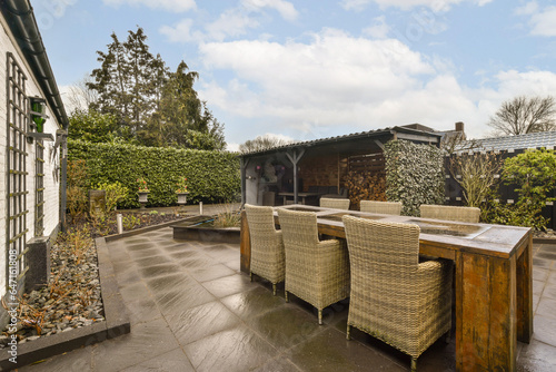 a patio with wickers on the table and chairs in front of an outdoor dining area under a cloudy blue sky