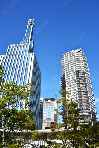 都会の高層タワービルとマンション 晴れた日の澄んだ青空と緑の木々が美しい