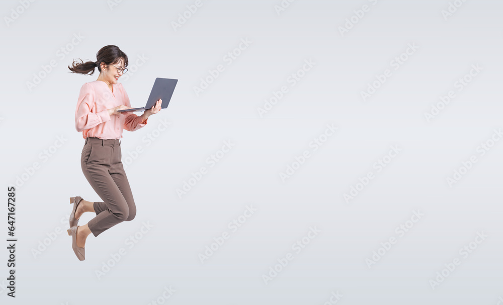 ノートパソコンを使いながらジャンプするミドル女性（切り抜き背景透過PNGも販売しております。作成者リンクから「PNG」で検索してください）