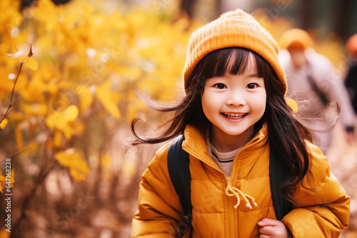 Little girl smile playing at park in autumn morning, yellow jacket