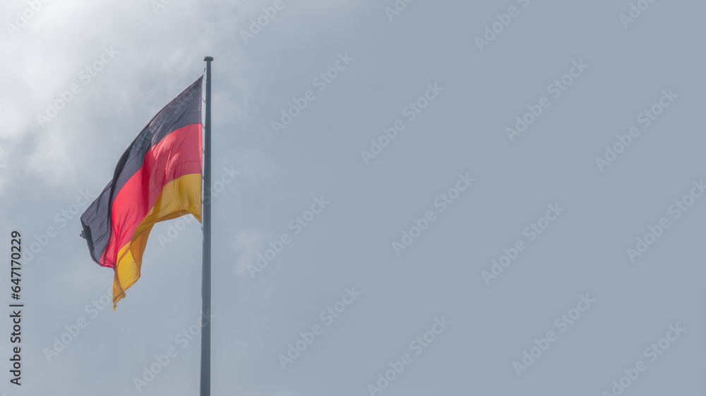 Naklejka premium National black red yellow flag of Germany and at dramatic sky solid background with copy space. Concept of nationality, citizenship and economical crisis and recession