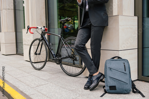 Businessman in a suit standing near the bike