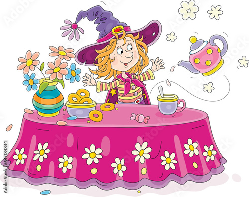 Funny little witch at her festive table with a tea cup, a flying magical teapot, a flower vase and tasty fresh pastry, vector cartoon illustration isolated on a white background