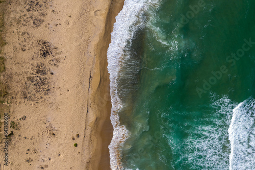 Aerial view of a remote sandy beach and sea waves