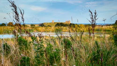 Dunstanburgh Castle beyond Embleton Quarry Nature Reserve, a former whinstone quarry the new reserve is a tribute to the local community in the coastal village of Embleton who developed the site