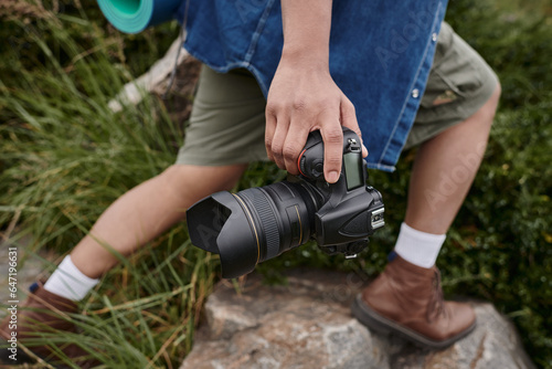 travel and photography concept, cropped view of man holding camera and standing in natural place