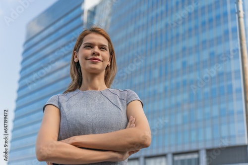 Portrait of a young and successful white caucasian business woman standing in front of a modern cityscape of office buildings Free Download Portrait of a young and successful white caucasian business woman standing in front of a modern cityscape of office buildings - GFXLoad