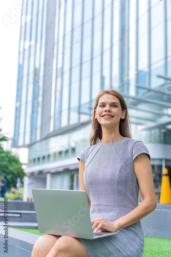 Young caucasian businesswoman working remotely outside her office building 