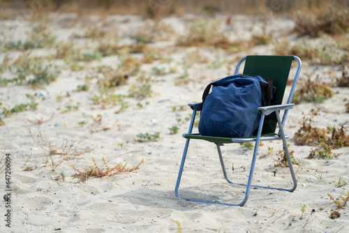 Fototapeta Naklejka Na Ścianę i Meble -  travel chair on a beach with a backpack on it.