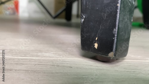 Old wooden scratched black colour chair leg sliding on ground floor close up view indoor with copy text space. Furniture and home design concept. 