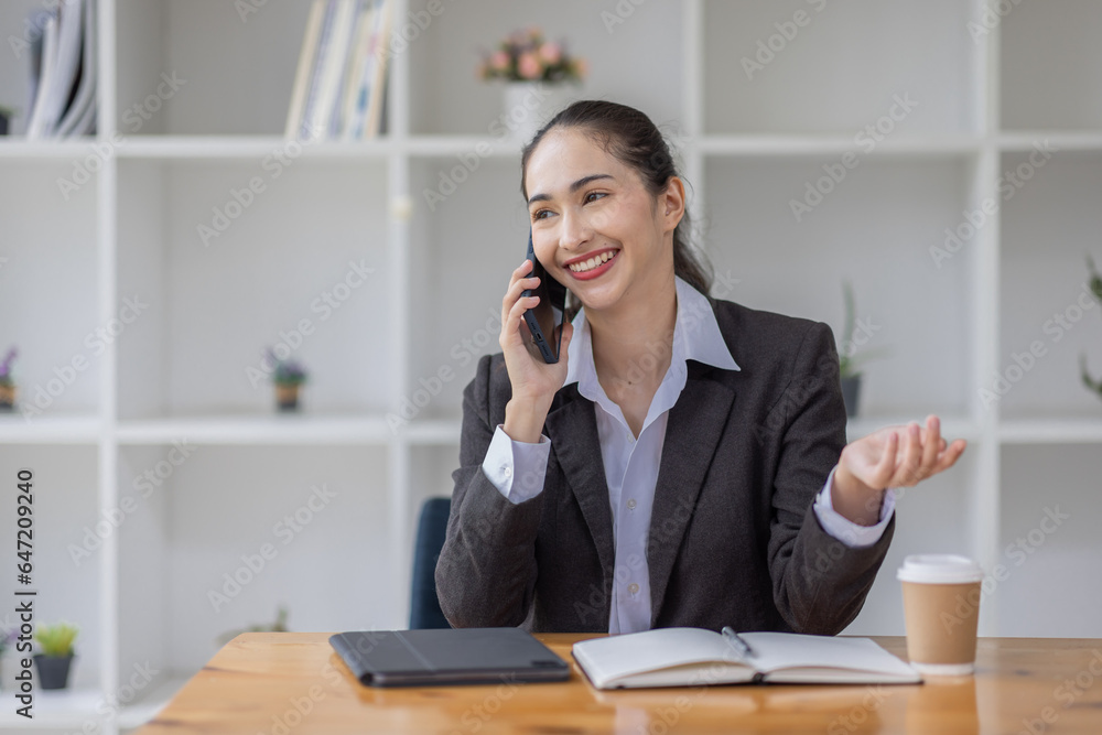 Cheerful business Asian woman freelancer making telephone call share good news about project working in office workplace, business finance concept.	