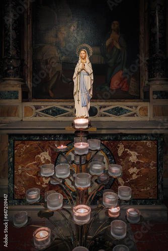 Obraz na plátně Statuette of the Madonna with votive candles