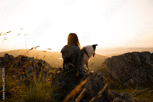 jóven con perro en lo alto de la montaña disfrutando del atardecer
