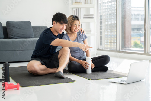 Couple resting after exercising at home Watch sports videos online Point to the screen Talk about exercise © seksan94