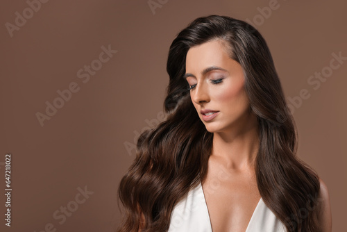Hair styling. Beautiful woman with wavy long hair on brown background, space for text