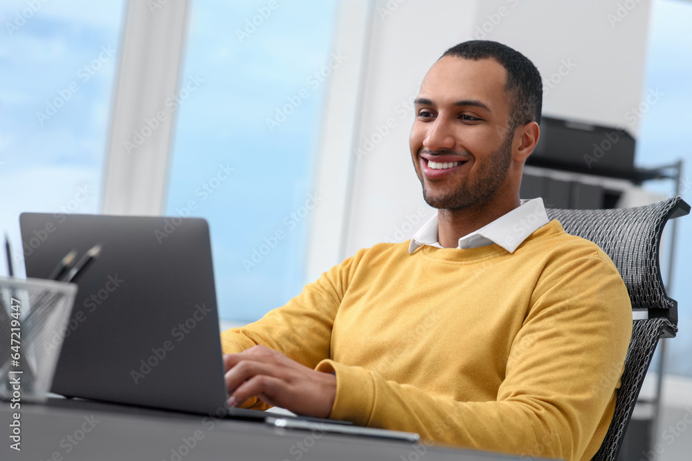 Fototapeta premium Young man working on laptop at table in office