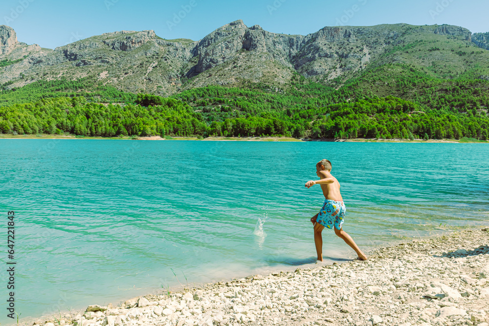 teenager in shorts walks near mountain lake against the backdrop of a beautiful landscape beautiful