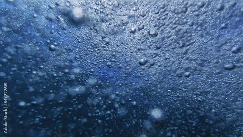 Gradual ascent of air bubbles in slow motion, moving from the sea floor up to the water surface, with sunlight filtering through. Great for creating an abstract natural backdrop.