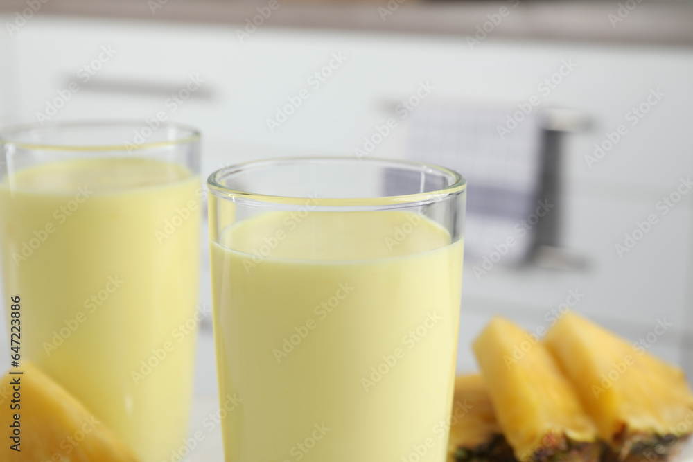 Glasses of tasty pineapple smoothie on blurred background, closeup