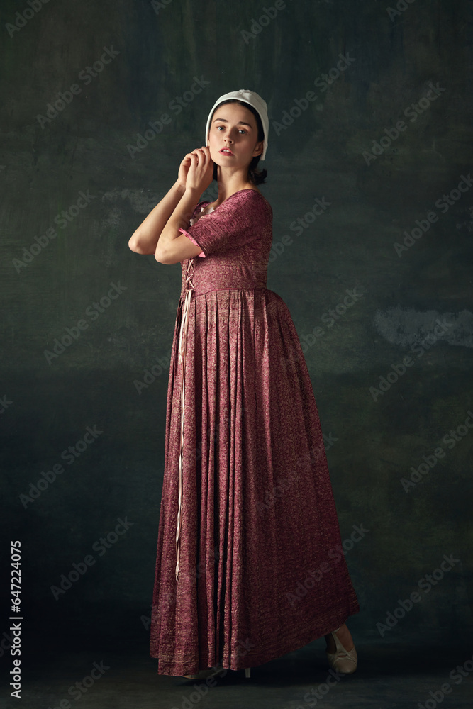 Portrait of elegant woman in image of medieval maid, wearing vintage costume against dark vintage background. Tenderness. Concept of history, comparison of eras, beauty, art, creativity Portrait of elegant woman in image of medieval maid, wearing vintage costume against dark vintage background. Tenderness. Concept of history, comparison of eras, beauty, art, creativity
