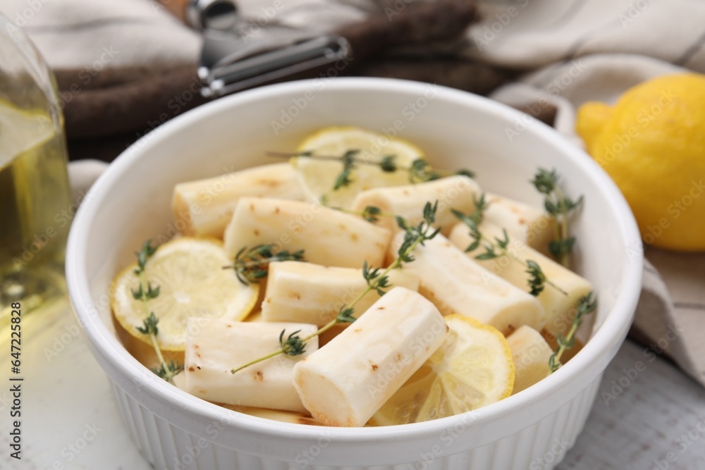 Dish with raw salsify roots, lemon and thyme on table, closeup Dish with raw salsify roots, lemon and thyme on table, closeup