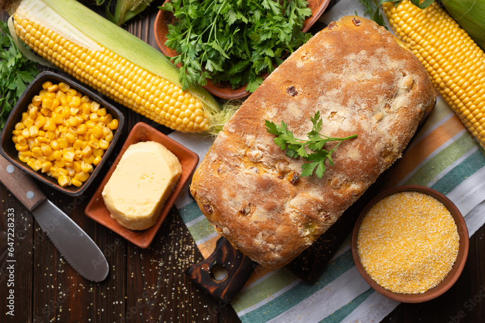Cut board with fresh cornbread on wooden kitchen table flat lay view