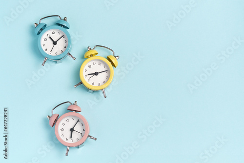 Three alarm clocks of different colors show different times. Start of the day, waking up, morning, different time zones. photo