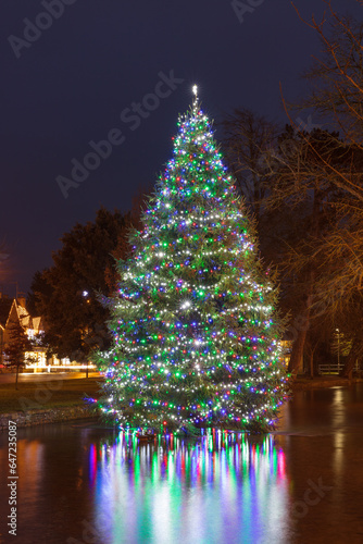 Christmas tree in the River Windrush, in the Gloucestershire village of Bourton-on-the-Water. Lights reflecting in water at night.