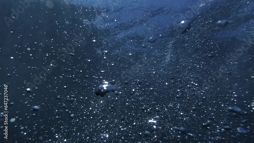 Slow motion of air bubbles glittering and shining while rising up to the sea water surface from ocean bottom.