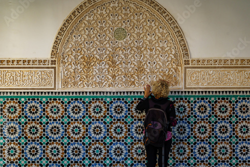 Morocco. Marrakesh. Madrasa Ben Youssef. The largest and most important madrassah in Morocco. A woman tourist look at the koranic writing photo