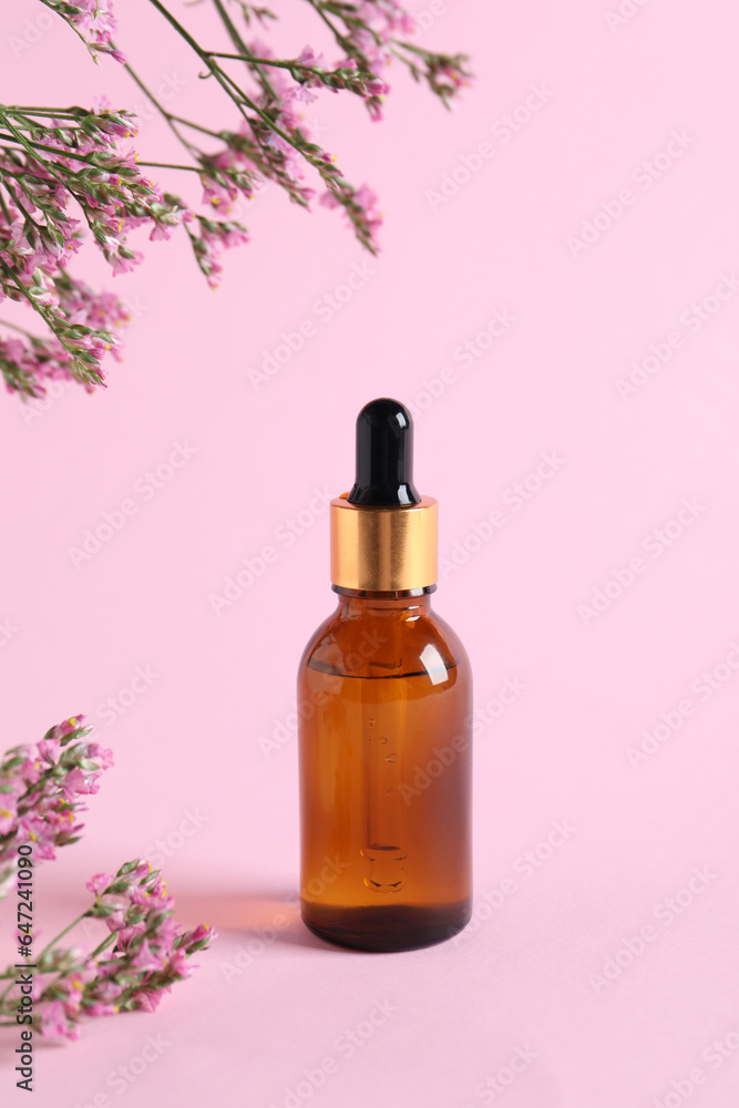 Bottle with cosmetic oil and flowers on pink background Bottle with cosmetic oil and flowers on pink background