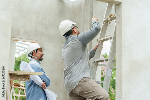 Wallpaper Mural Asian construction supervisor Climb the ladder and point out the problem area. Consultation of a bearded Indian engineer wearing a helmet. Let workers rush to build houses in the construction area. Torontodigital.ca