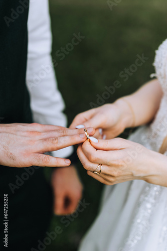 The bride puts a gold ring on her finger at the ceremony. Wedding photography of the newlyweds, close-up portrait.