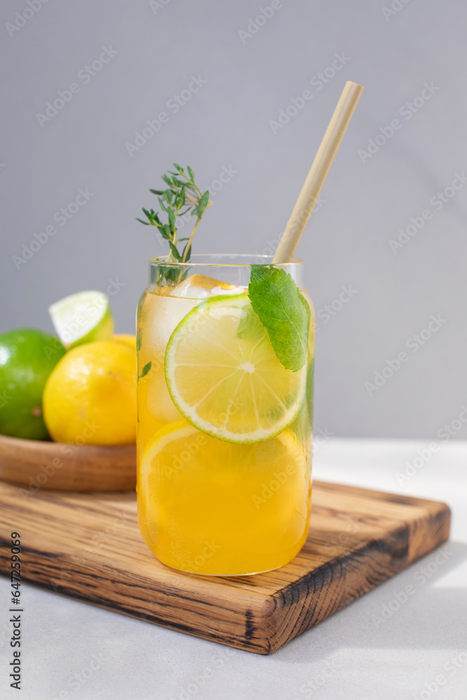 Fototapeta premium Drink with orange lemon and lime in glass transparent glasses on a concrete background. Lemonade with ice. Front view