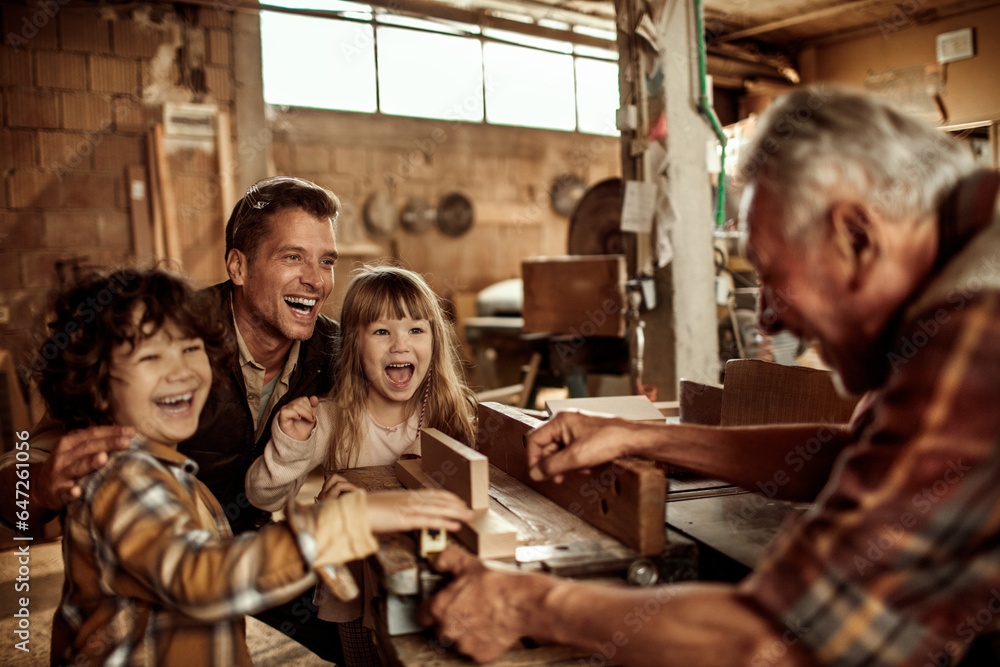 Grandfather carpenter teaching his son and grandchildren how to work with wood in a wood workshop Grandfather carpenter teaching his son and grandchildren how to work with wood in a wood workshop