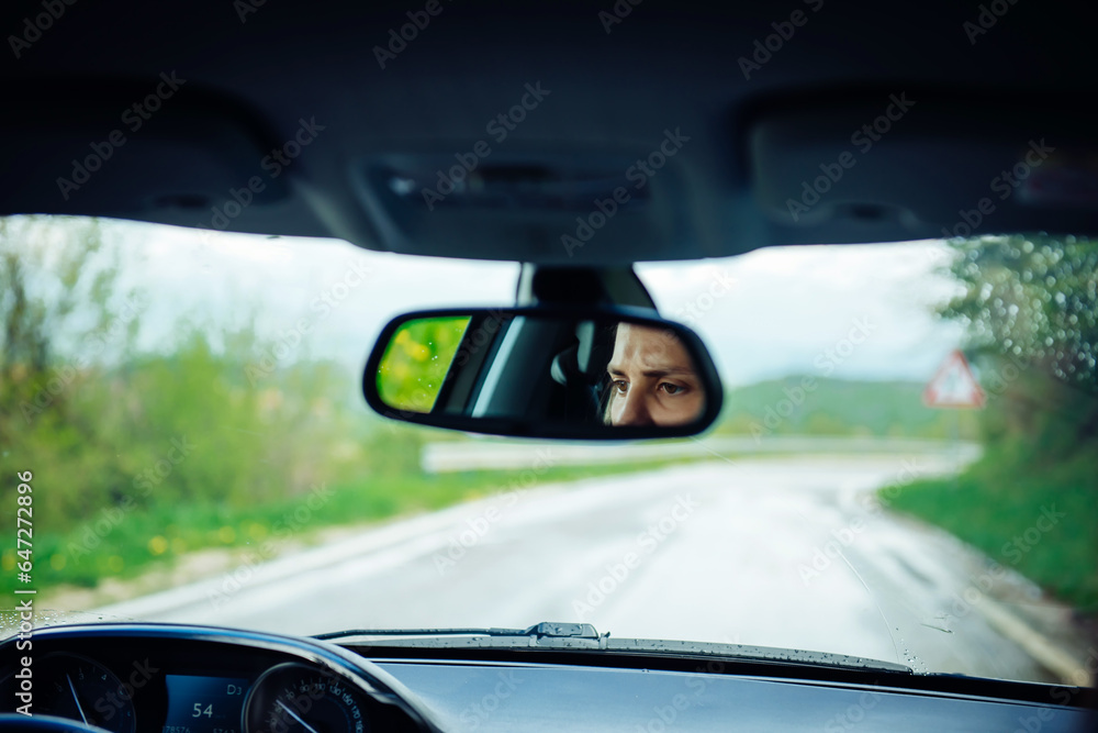 Attentive eyes of a female driver in the rearview mirror while driving, traveling by car Attentive eyes of a female driver in the rearview mirror while driving, traveling by car