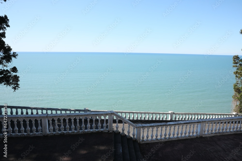 White railings and stairs near calm sea on sunny day