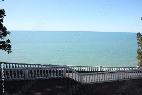 White railings and stairs near calm sea on sunny day