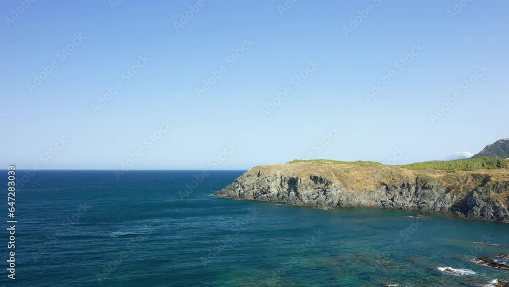 The rocky coast without vegetation in Europe, in France, in Occitanie, in the Pyrenees Orientales, in Banyuls-sur-Mer, at the edge of the Mediterranean Sea, in summer, on a sunny day. The rocky coast without vegetation in Europe, in France, in Occitanie, in the Pyrenees Orientales, in Banyuls-sur-Mer, at the edge of the Mediterranean Sea, in summer, on a sunny day.