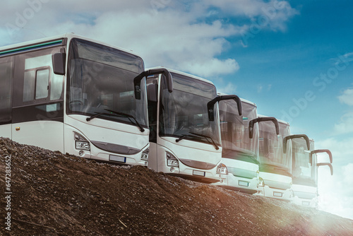 fuhrpark von bussen in einer reihe auf einem hügel bei strahlenden sonnenschein und blauen himmel