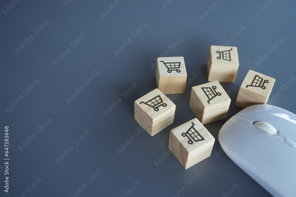 Computer mouse and wooden cubes with shopping trolley icon. Copy space. Online shopping and business concept Computer mouse and wooden cubes with shopping trolley icon. Copy space. Online shopping and business concept