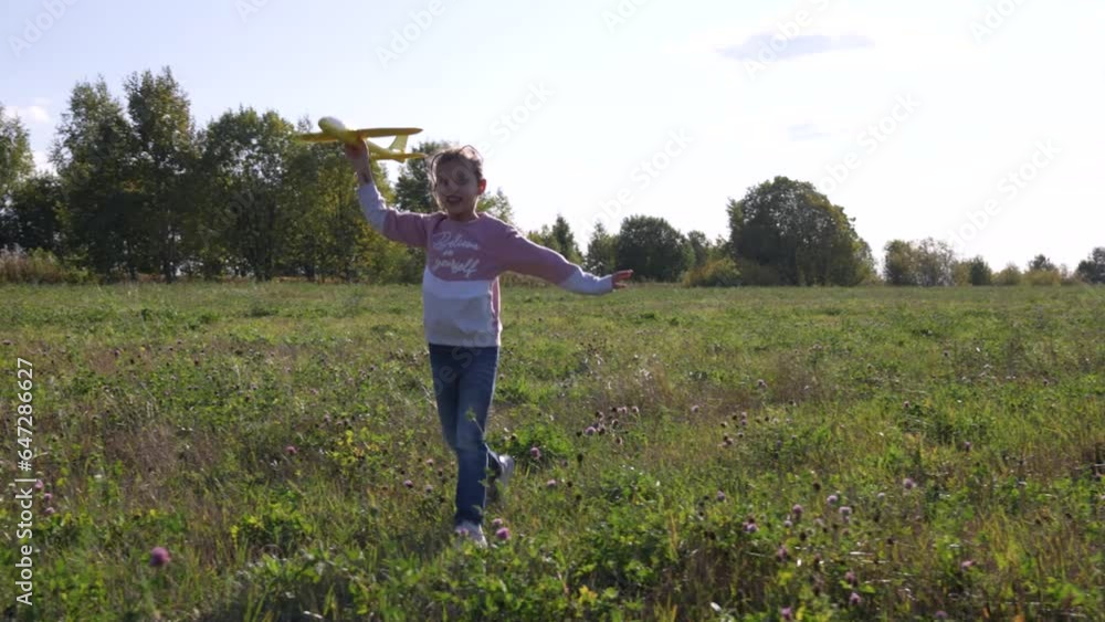 Child runs with toy plane in hand in summer field Child runs with toy plane in hand in summer field
