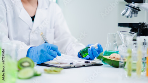 Female scientist is checking the quality of gel, oil or serum to test and develop fruits skin care essence, moisturizer, medical, treatment to increase and control the quality of product in laboratory