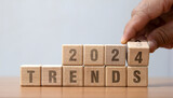 2024 trends new year symbol. Businessman turns a wooden cube and changes words Trends 2023 to Trends 2024. Beautiful grey table grey background, copy space. Business 2024 trends new year concept.