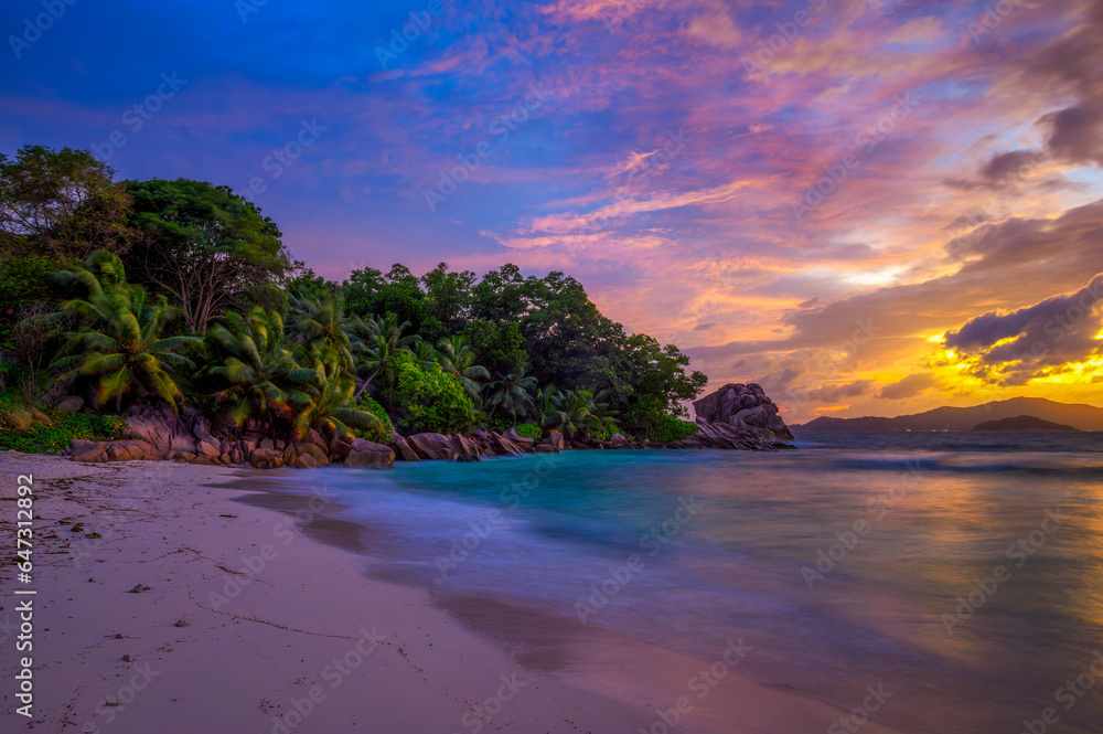 Colorful sunset over Anse Severe Beach at the La Digue Island, Seychelles. This beautiful white-sand beach is famous for its turquoise, shallow waters and sunset views. Long exposure.